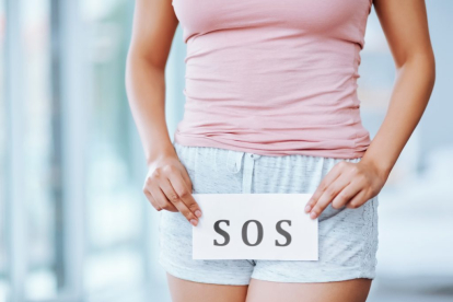 Cropped shot of an unrecognizable woman holding an SOS sign in front of her private parts
